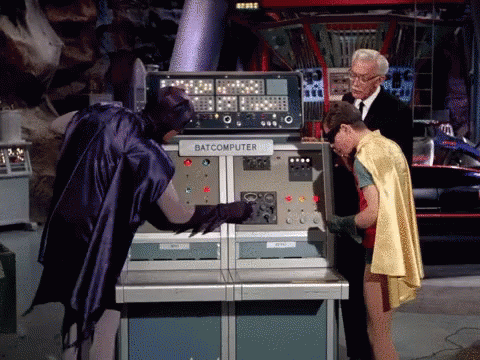 Batman '66, Robin, and Alfred at the Bat Computer. Batman is turning a crank to make an answer come out.