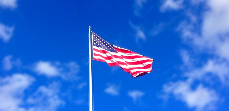Decorative image of American flag flying, blue sky background