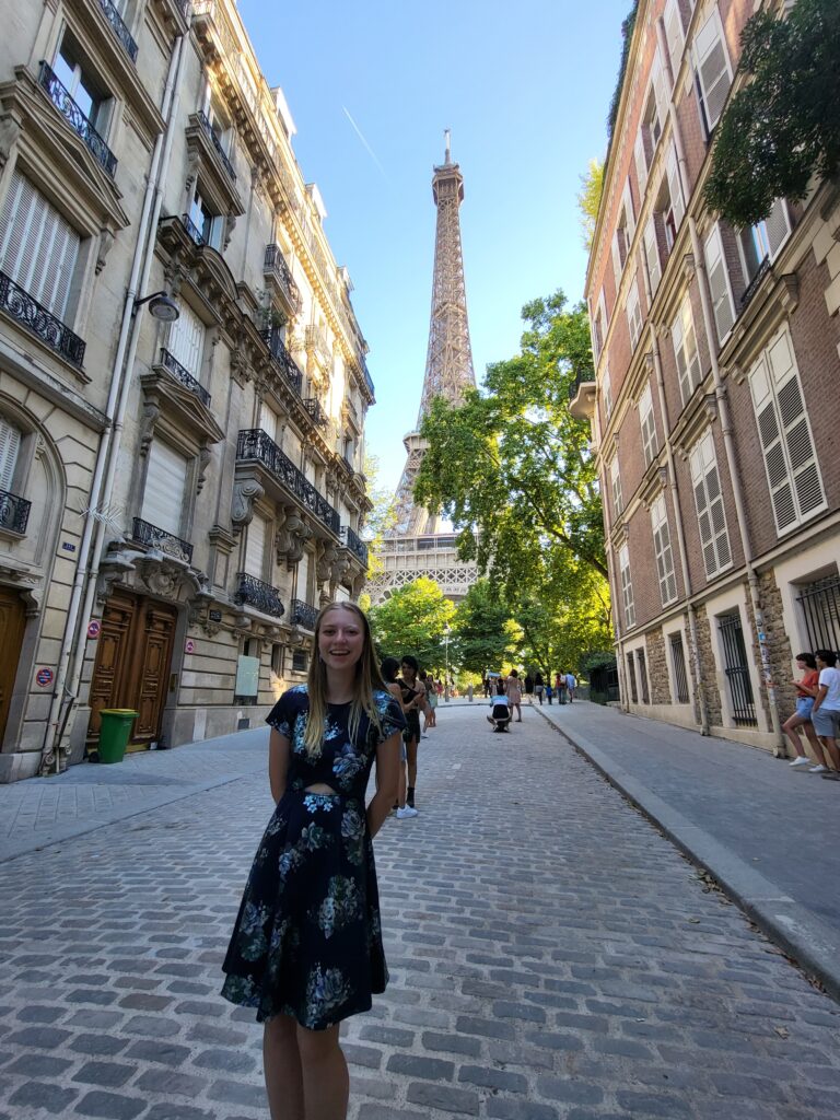Katherine Hartley standing on Paris street with Eiffel Tower in background