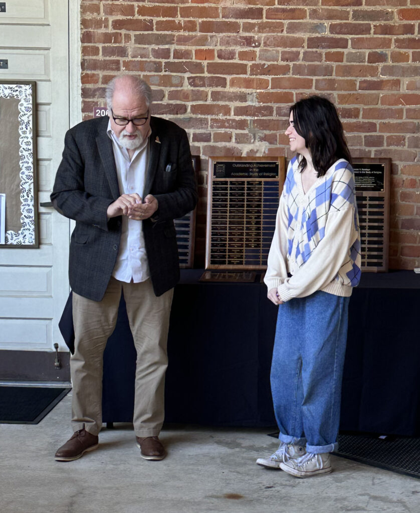 Photo of a student receiving a button award from a professor