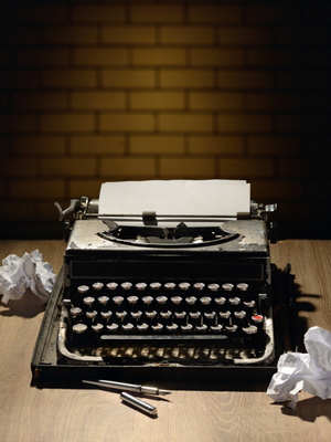 antique typewriter sitting on a desk, surrounded by crumpled sheets of paper