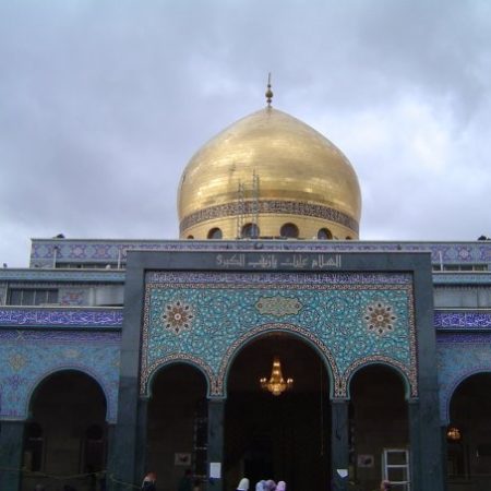 Front of mosque displaying arches, a gold dome, and a single minaret