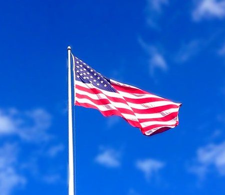 Decorative image of American flag flying, blue sky background